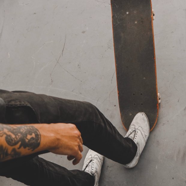 homem-braço-tatuado-com-skate