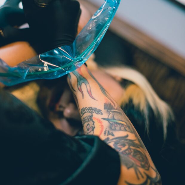 braco-tatuado-com-clip-cord-azul-maquina-de-tatuagem-luvas-pretas