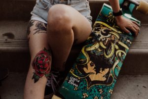 mulher-perna-e-jpeho-tatuado-ao-lado-de-um-skate