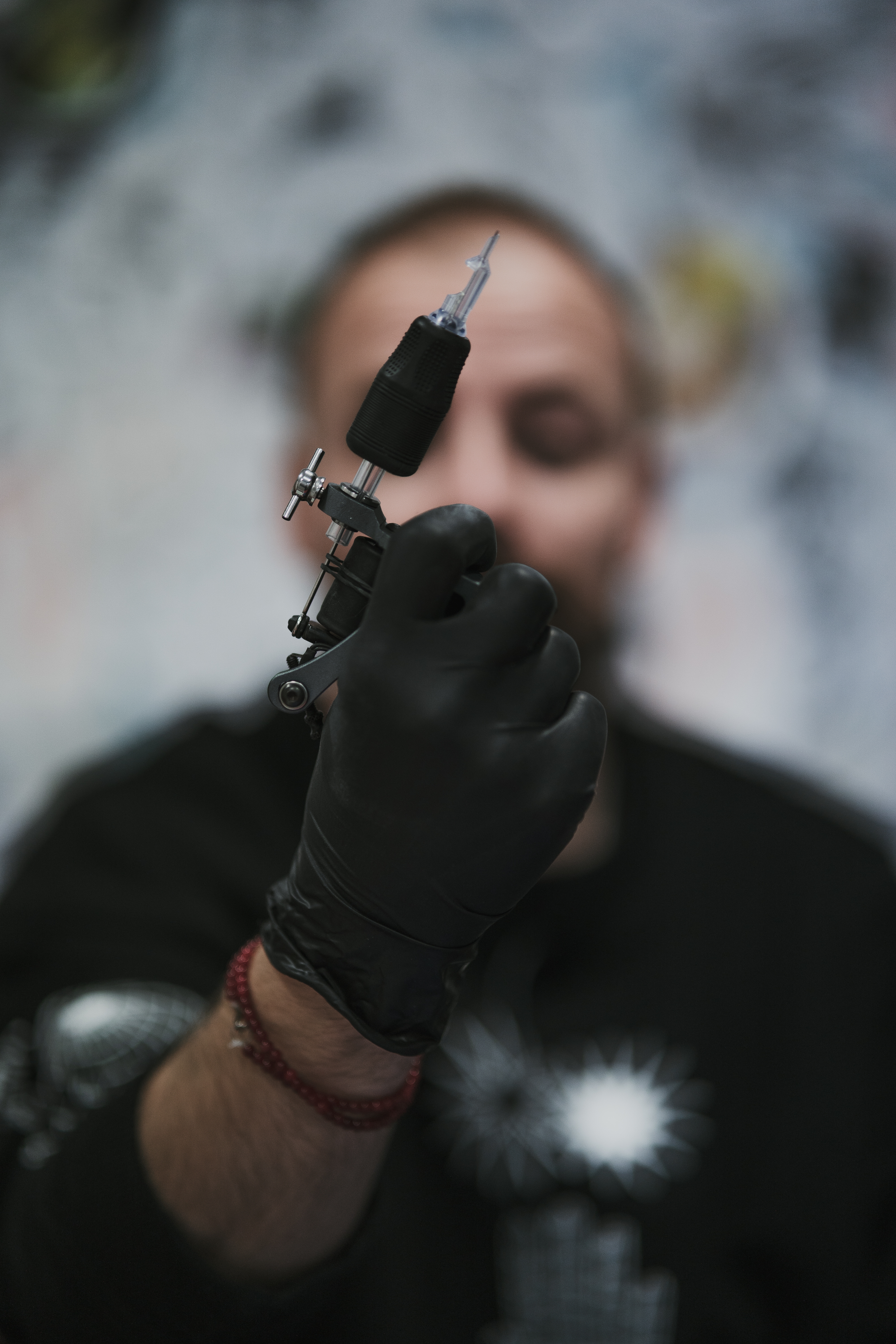foto-vertical-de-um-tatuador-profissional-com-luvas-de-latex-pretas-preparando-uma-maquina-para-tatuar.